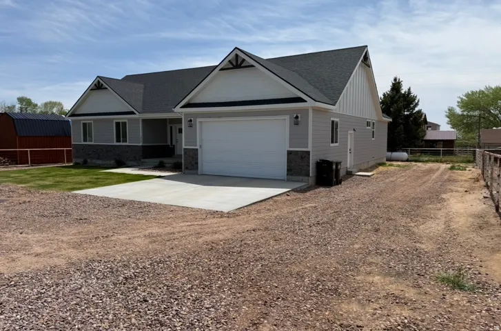 Contemporary ranch-style residence featuring light gray siding and dark stone veneer accents