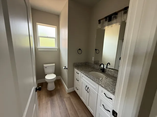 Bathroom featuring a double vanity with white cabinetry, granite countertop, and integrated sink