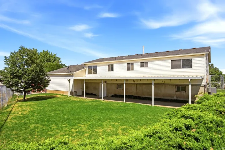 Expansive backyard featuring a manicured lawn, established landscaping, and mature trees