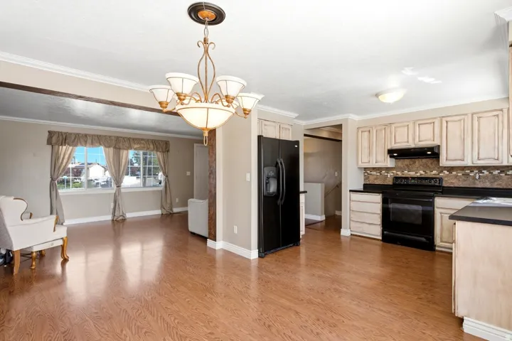Kitchen and dining area featuring wood-finish flooring, white cabinetry, dark countertops, and a black appliance suite