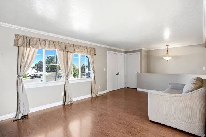 Spacious room featuring wood-finish flooring, white baseboards, and a neutral wall palette