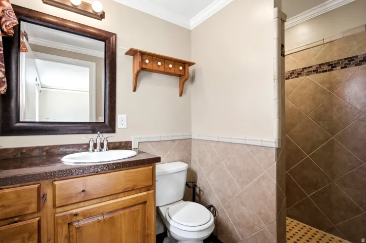 Bathroom featuring a wood vanity with an integrated sink, a dark countertop, and a framed mirror