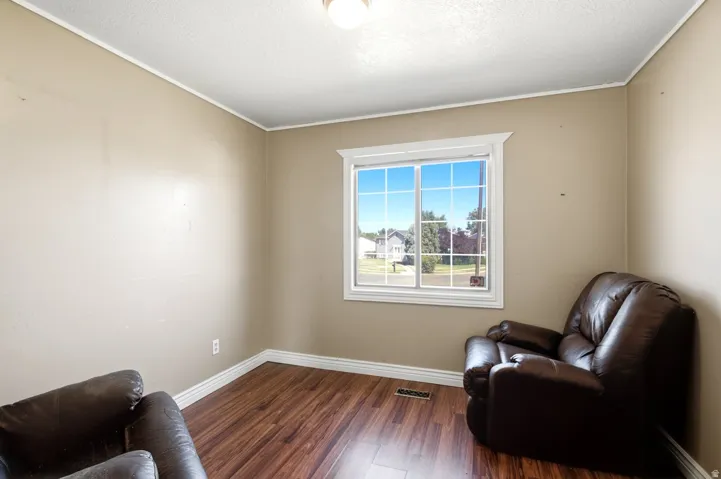 Bright interior space featuring a double-paned window with white trim, wood-finish flooring, neutral wall tones, and white baseboards
