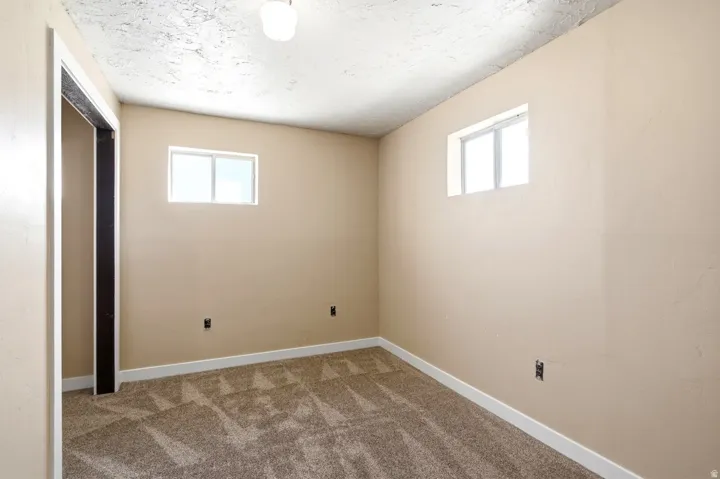 Room featuring two windows, neutral painted walls, textured ceiling, and patterned carpeting
