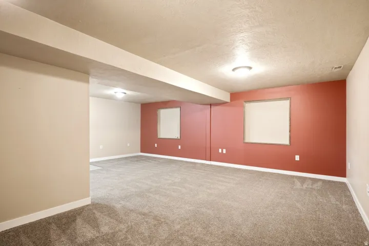 Spacious interior room with neutral-toned walls, contrasting accent wall, gray carpet, and recessed lighting