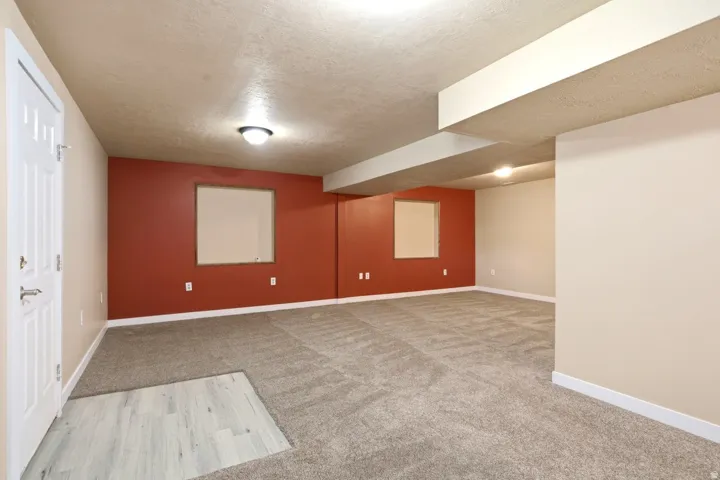 Spacious room featuring carpeting, recessed windows, a white paneled door, and overhead lighting