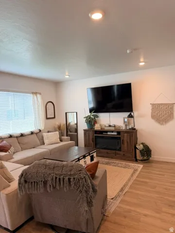 Living area featuring wood-finish flooring, recessed ceiling lighting, and a window with blinds