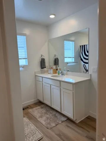 Bathroom featuring a white vanity with a single sink, light-toned countertop, and an expansive wall mirror