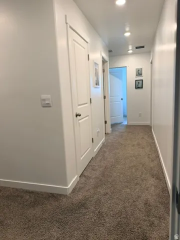 Hallway featuring recessed lighting, white walls, white trim, white paneled doors, and brown carpeting