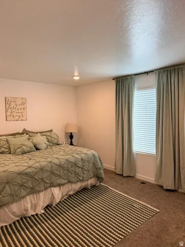 Recessed lighting illuminates a carpeted interior featuring a window with horizontal blinds and a curtain rod