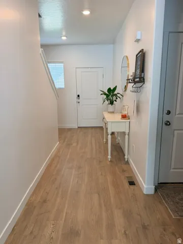 Entryway featuring wood-finish flooring, recessed lighting, and a white paneled door