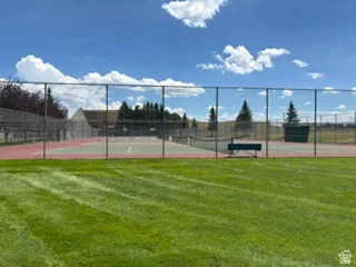 Community tennis courts featuring chain-link fencing, a green playing surface, and red perimeter