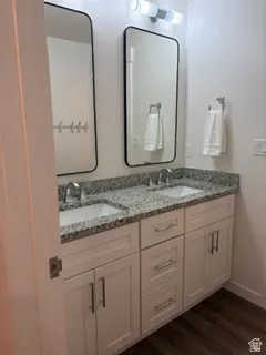 Dual vanity featuring white shaker-style cabinetry, a speckled countertop, and integrated sinks with chrome faucets
