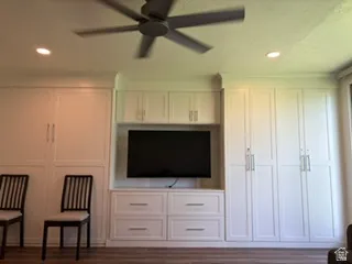 Integrated white cabinetry and media center featuring recessed lighting, a ceiling fan, and wood-finish flooring