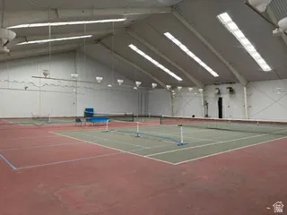 Indoor tennis court featuring a high vaulted ceiling with multiple skylights and overhead lighting