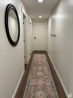 Hallway featuring wood-finish flooring, recessed lighting, and a white interior door