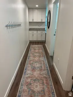 Hallway featuring wood-finish flooring, white walls, and a built-in cabinetry area