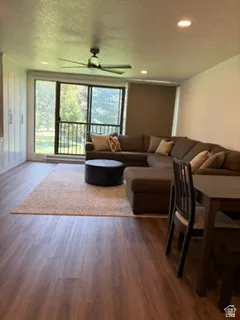 Spacious living area featuring wood-finish flooring and a ceiling fan with recessed lighting