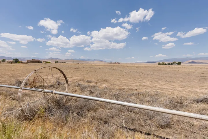 Expansive arid landscape featuring a clear sky with scattered clouds and distant mountain ranges