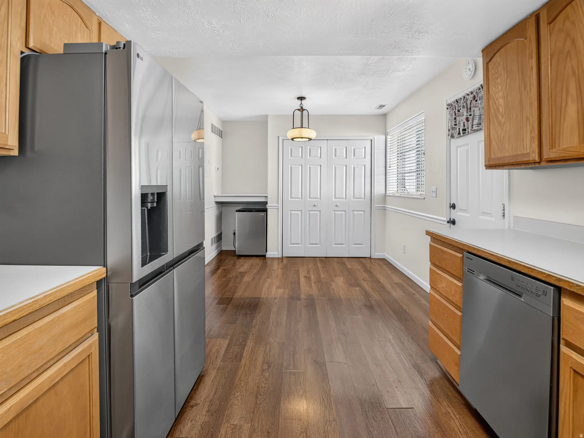 Kitchen area featuring wood-finish flooring, light wood cabinetry, light countertops, and stainless steel appliances