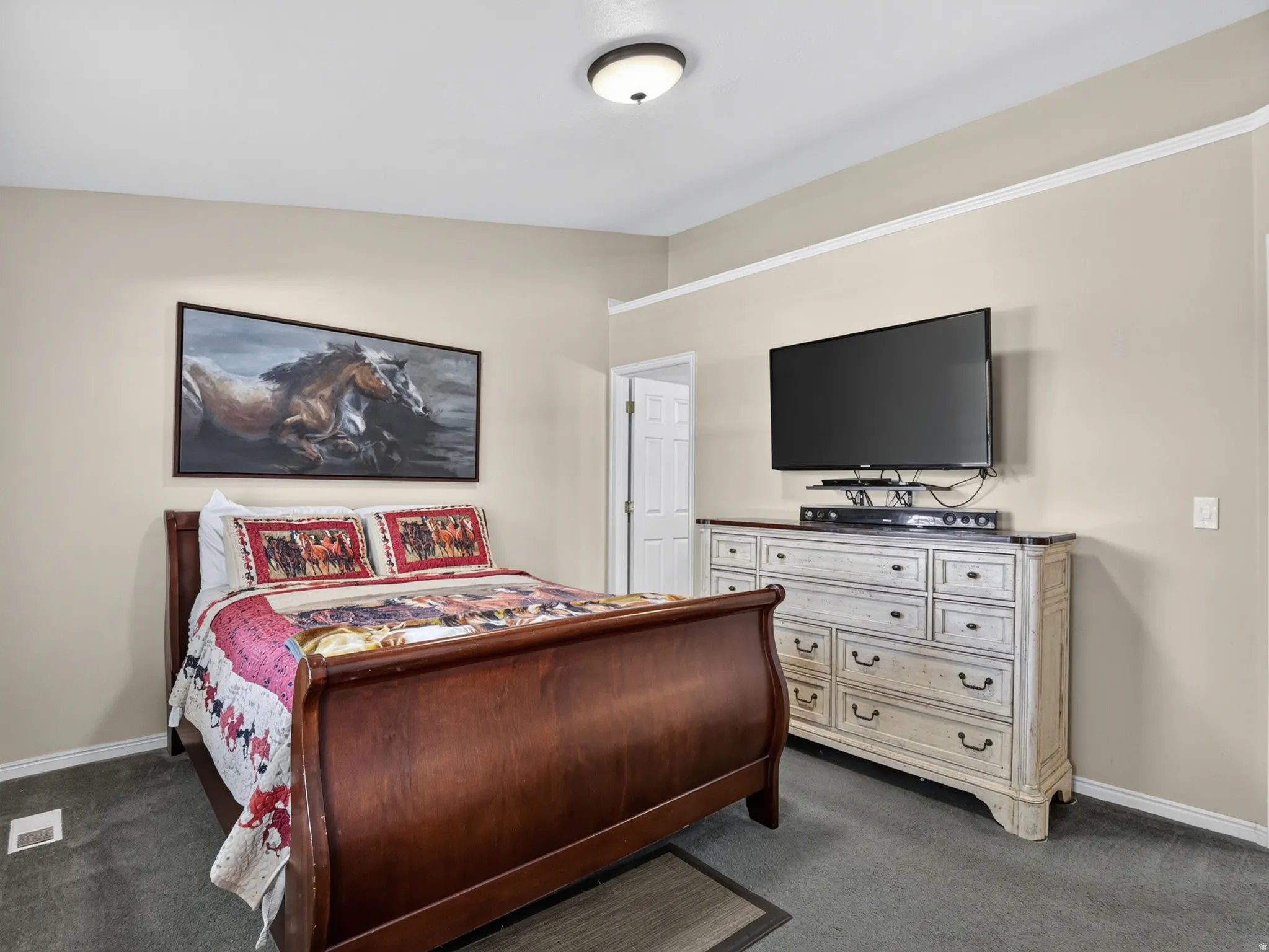 Neutral wall paint, crown molding, and dark gray carpeting create a cohesive aesthetic