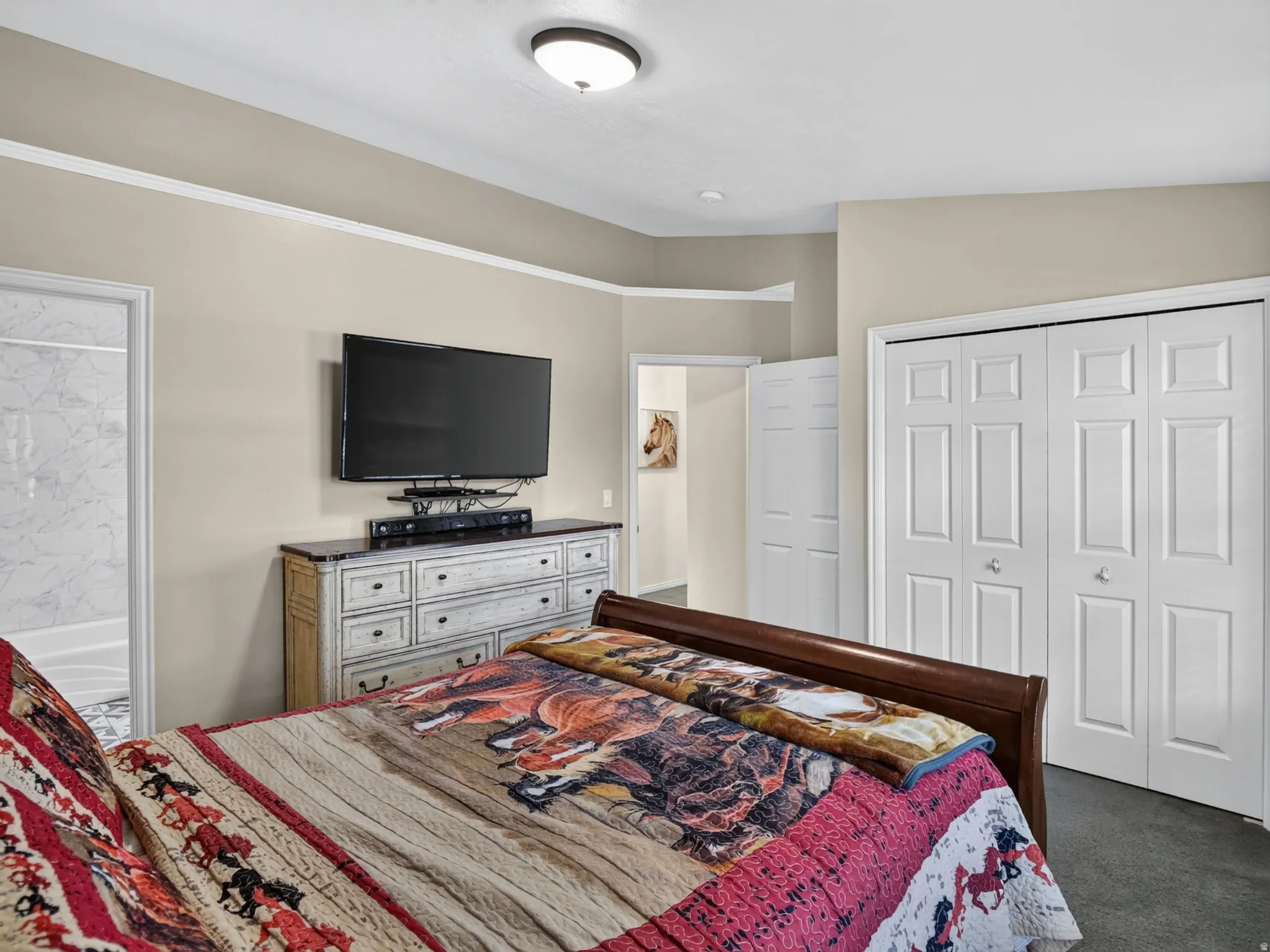 Master Bedroom featuring textured carpeting, neutral wall color, crown molding, and two-panel bi-fold closet doors