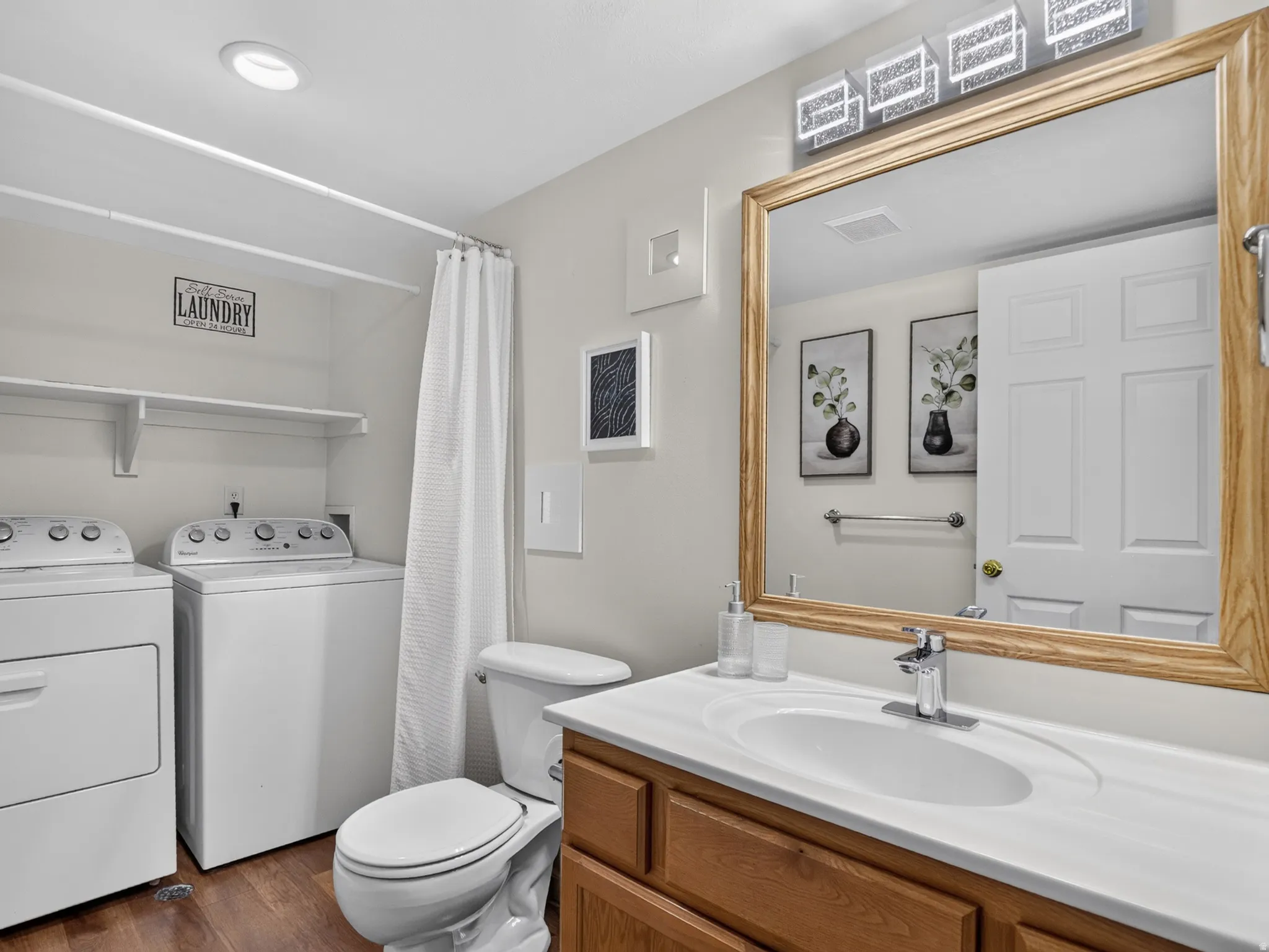Bathroom featuring a wood-finish vanity with an integrated sink, a large wood-framed mirror, and modern overhead lighting