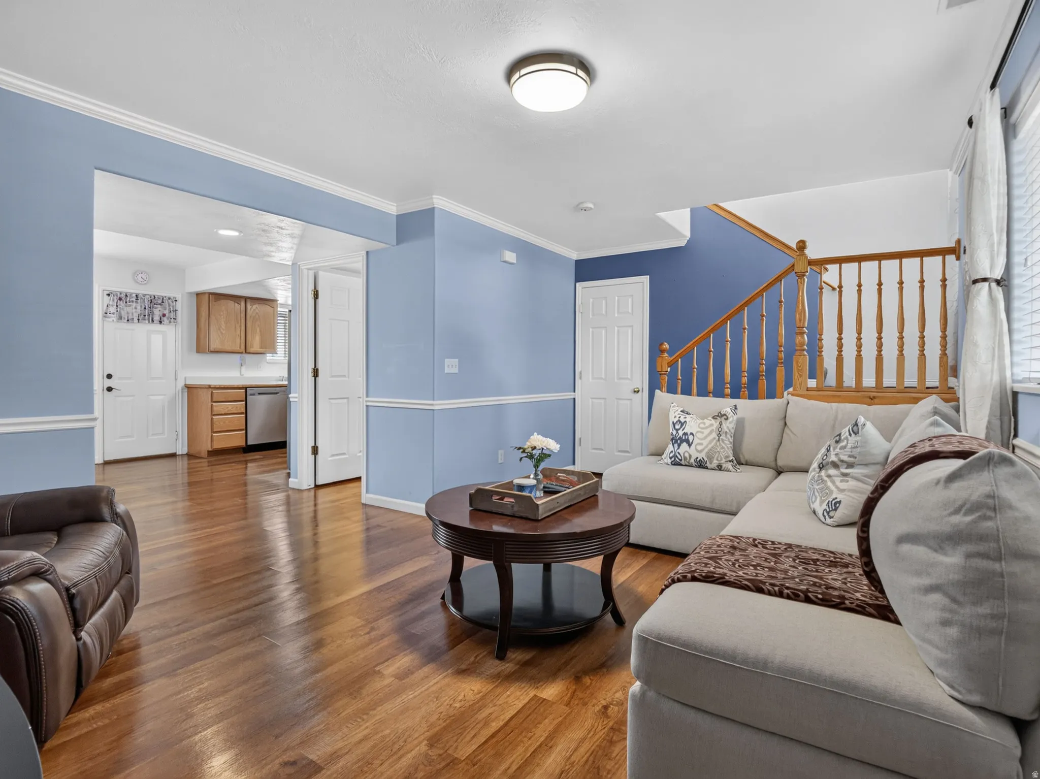 Spacious living area featuring wood-finish flooring, light blue and deep blue wall finishes, and white trim