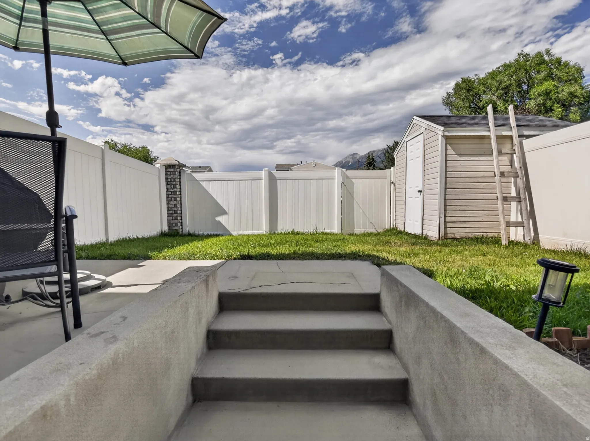 Concrete patio with steps leading to a fenced yard