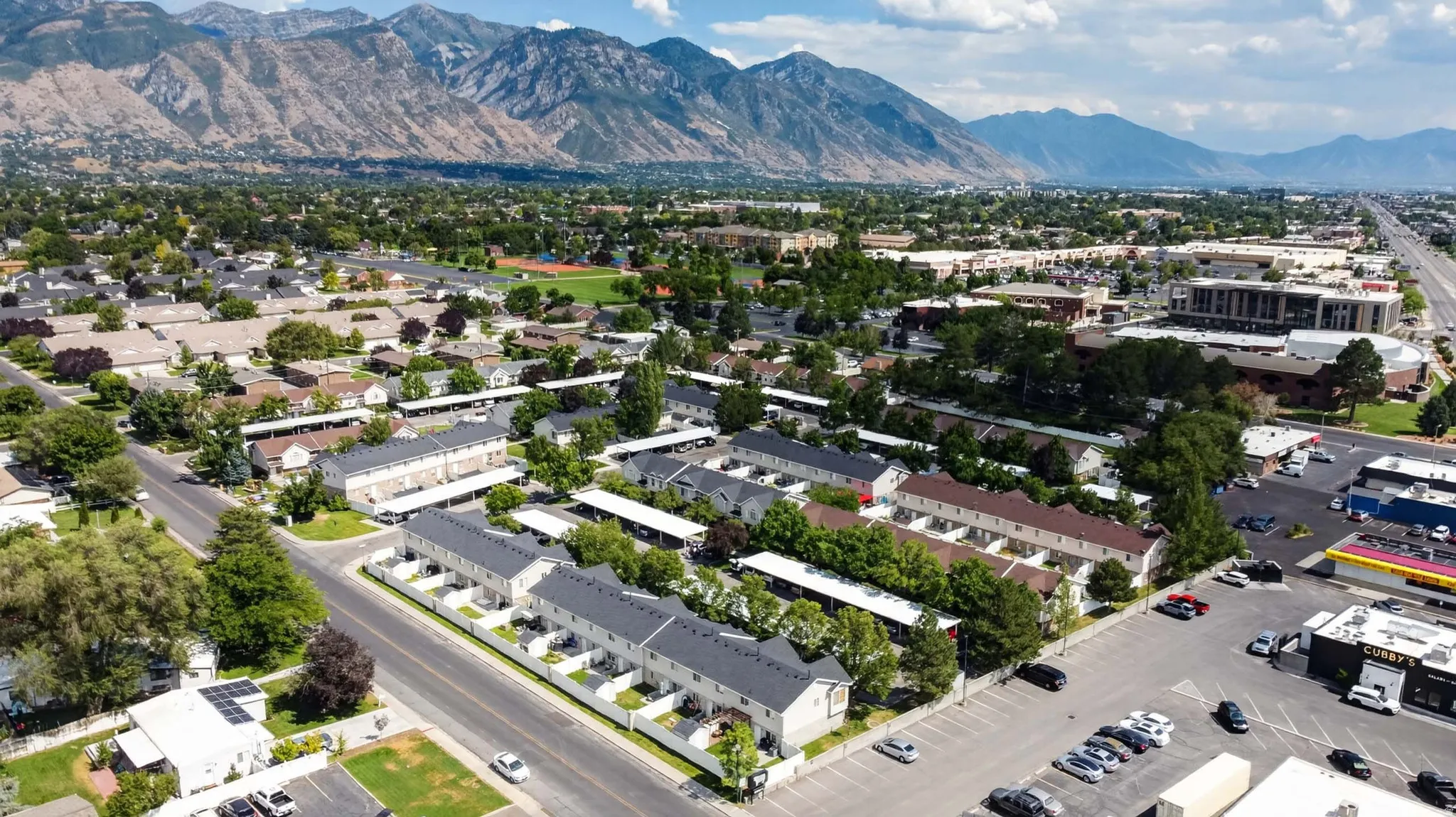 Suburban residential area with townhomes featuring white exterior finishes and private patio spaces