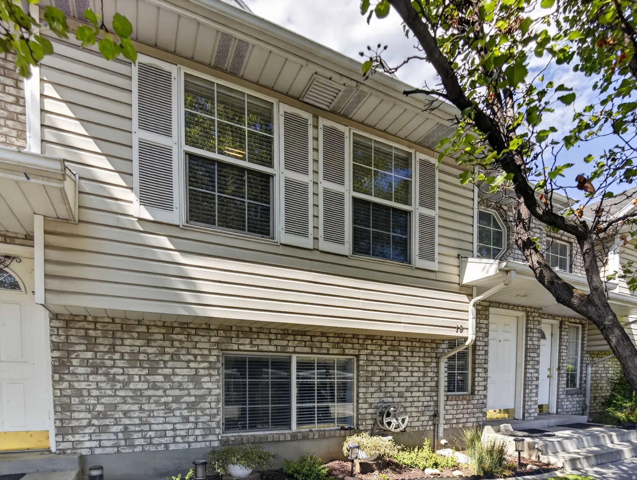 Beige horizontal siding exterior with a white brick base