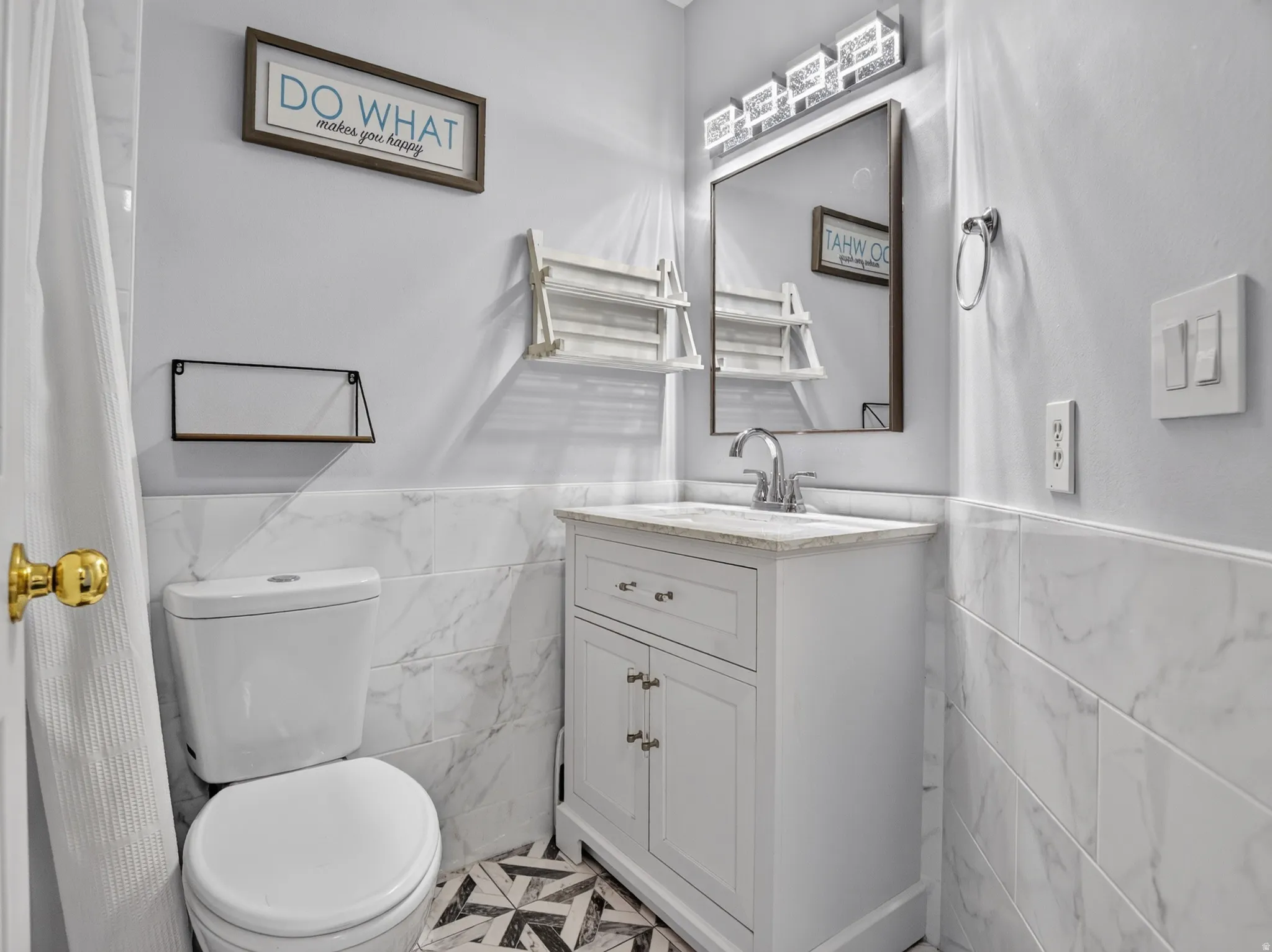 Hallway Bathroom featuring a white vanity with a light-toned countertop, a framed mirror, and a chrome faucet