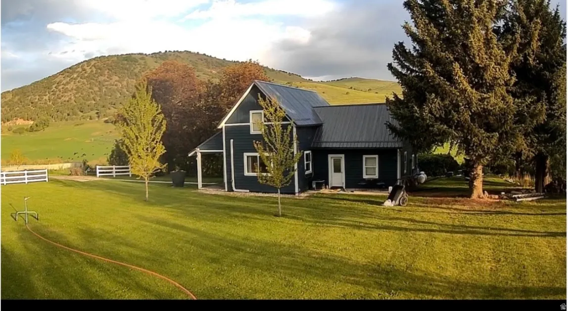 Two-story residence featuring dark siding, a dark metal roof, and white trim