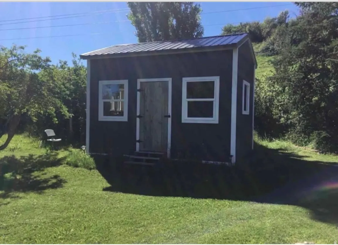 Freestanding outbuilding with dark siding and white trim