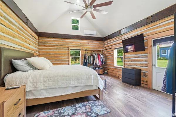 Interior space featuring log walls, vaulted white ceiling, and wood-finish flooring