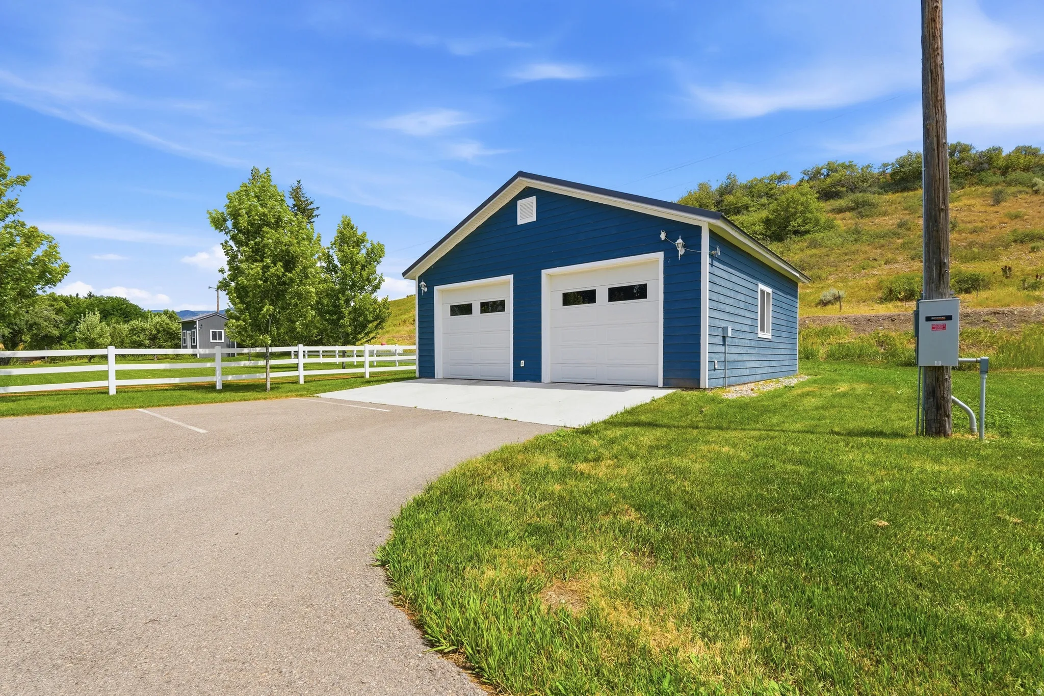 Detached two-car garage featuring a rich blue siding and crisp white garage doors