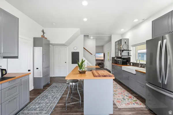 Spacious kitchen featuring gray cabinetry, wood-finish countertops, stainless steel appliances, and a farmhouse sink