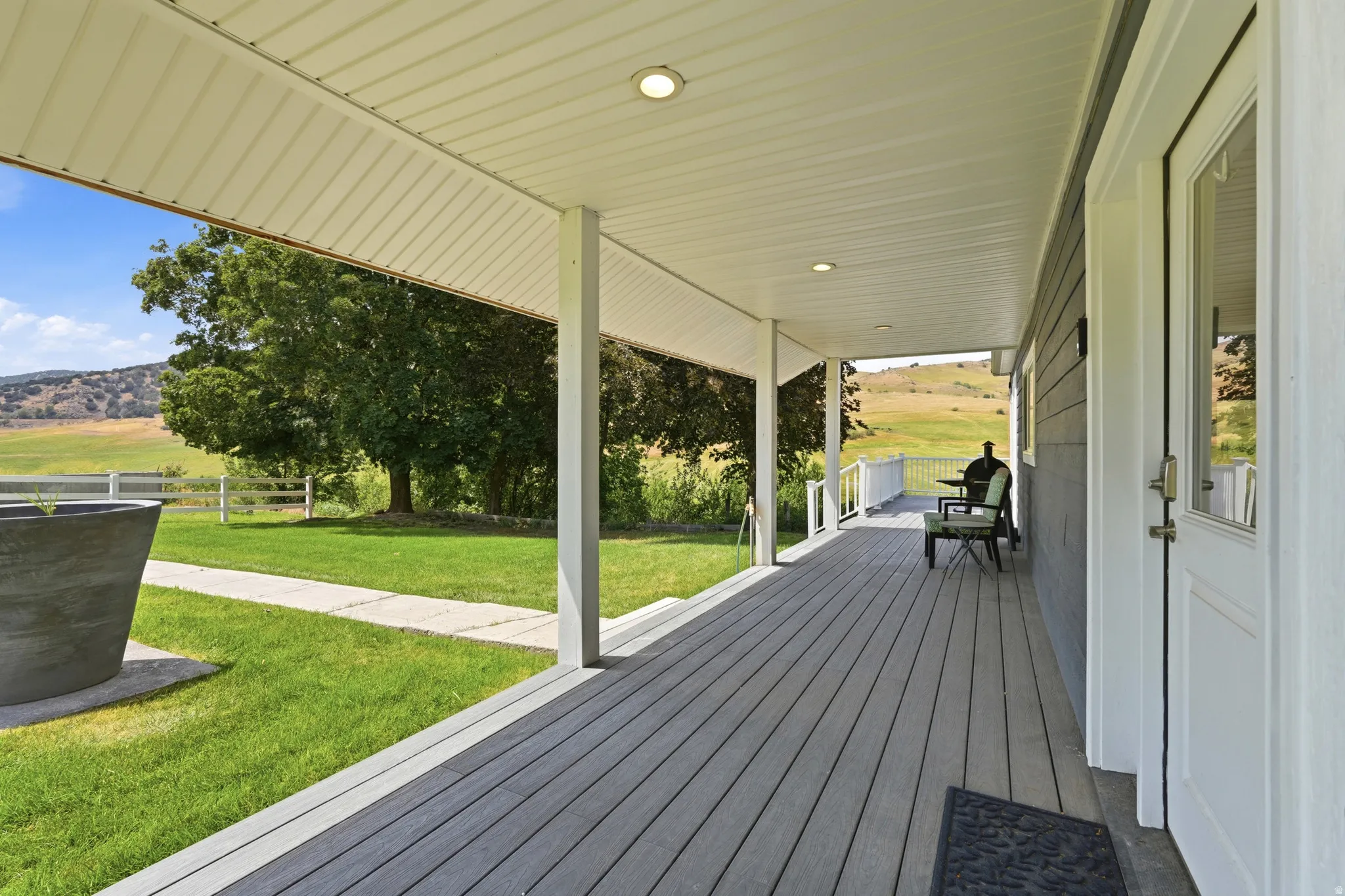 Covered front porch featuring composite decking, recessed lighting, and white support columns