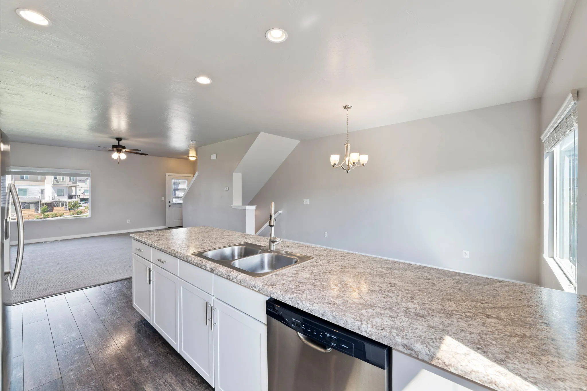 Kitchen island featuring a double-basin stainless steel sink, stainless steel dishwasher, and white cabinetry