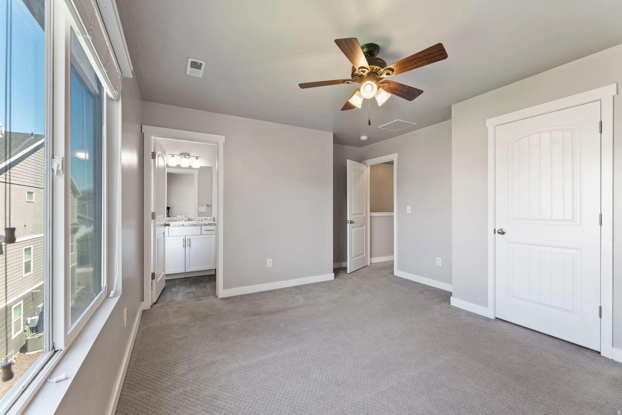 Primary  bedroom with multiple windows, a ceiling fan with integrated lighting, and white interior doors