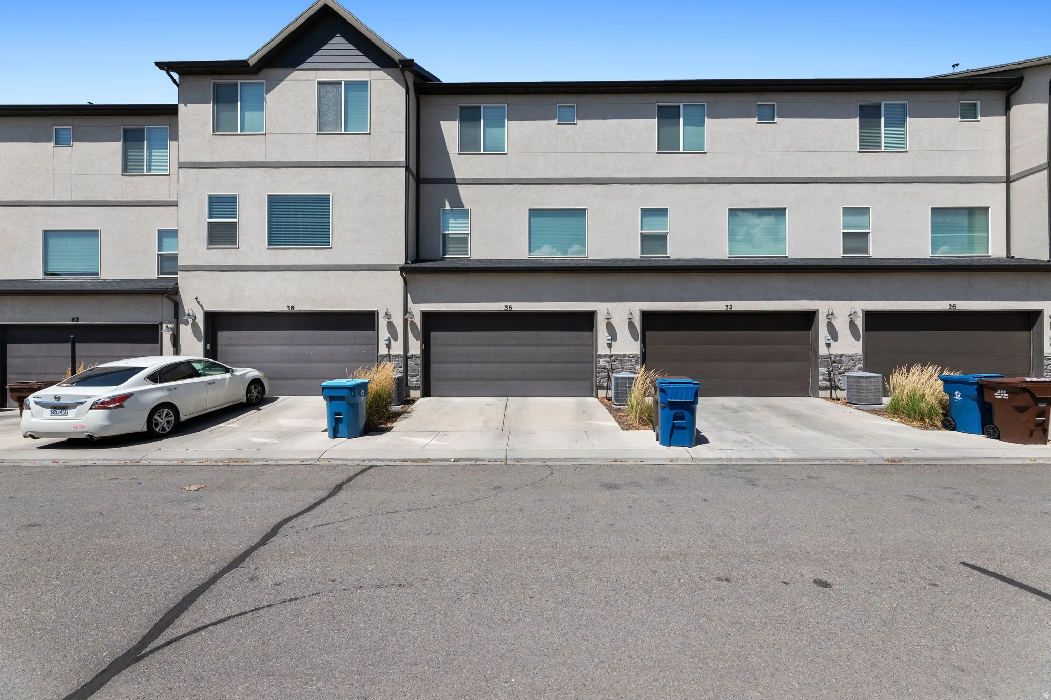 Multi-level townhome architecture featuring a light-colored stucco facade with dark trim accents and multiple windows