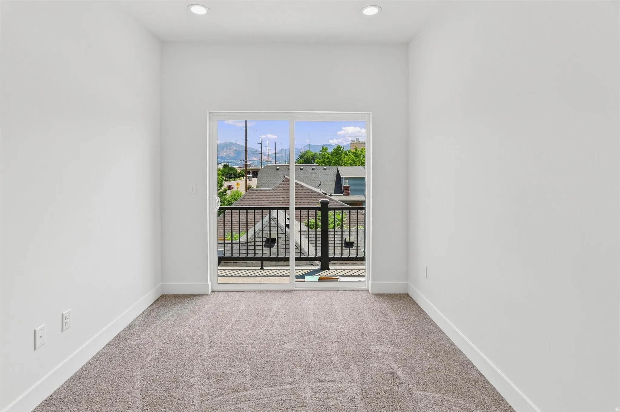 Sliding glass door opening to a private balcony with black iron railings