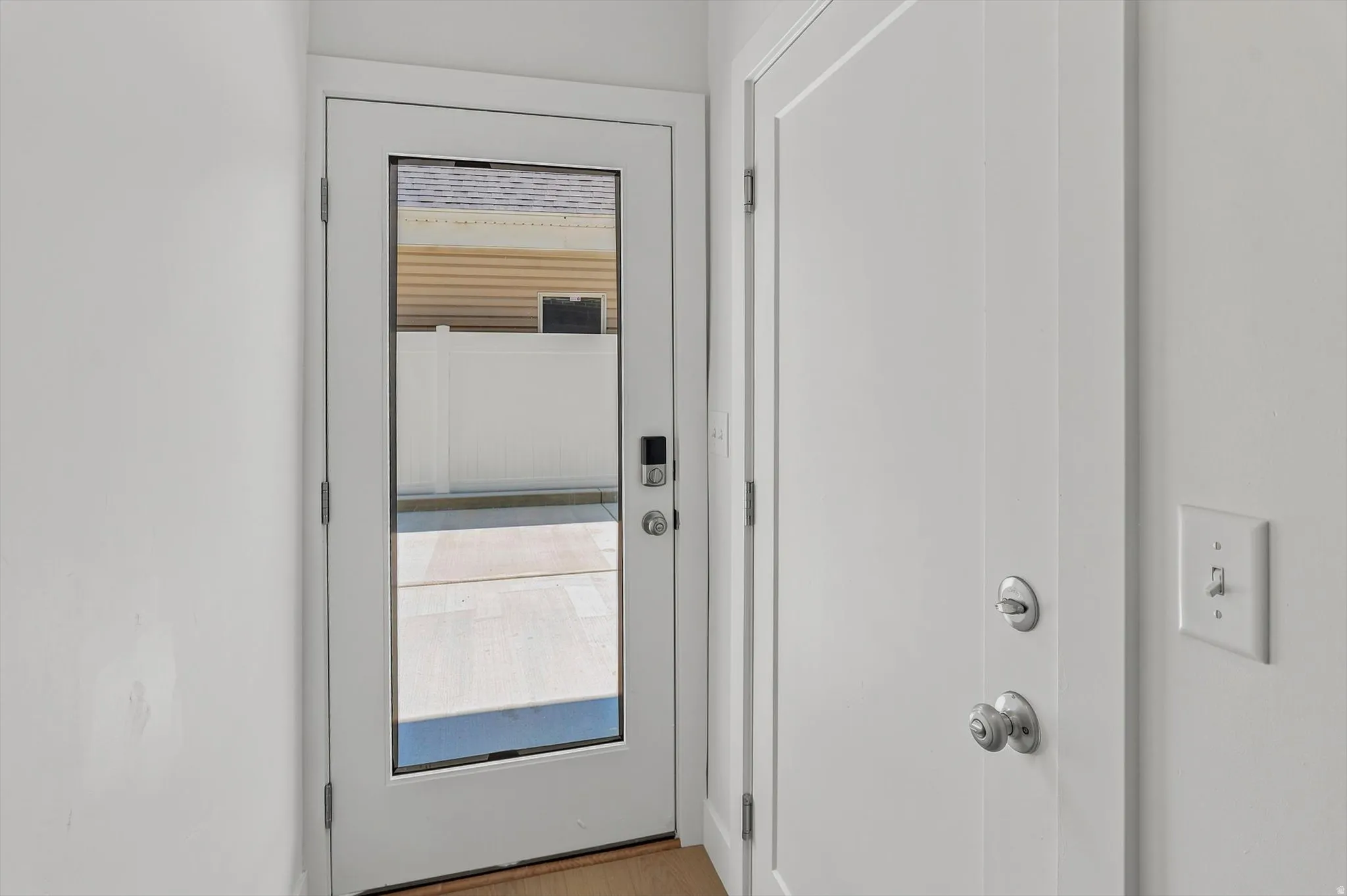 Full-light exterior door with a smart lock, complemented by crisp white trim and walls
