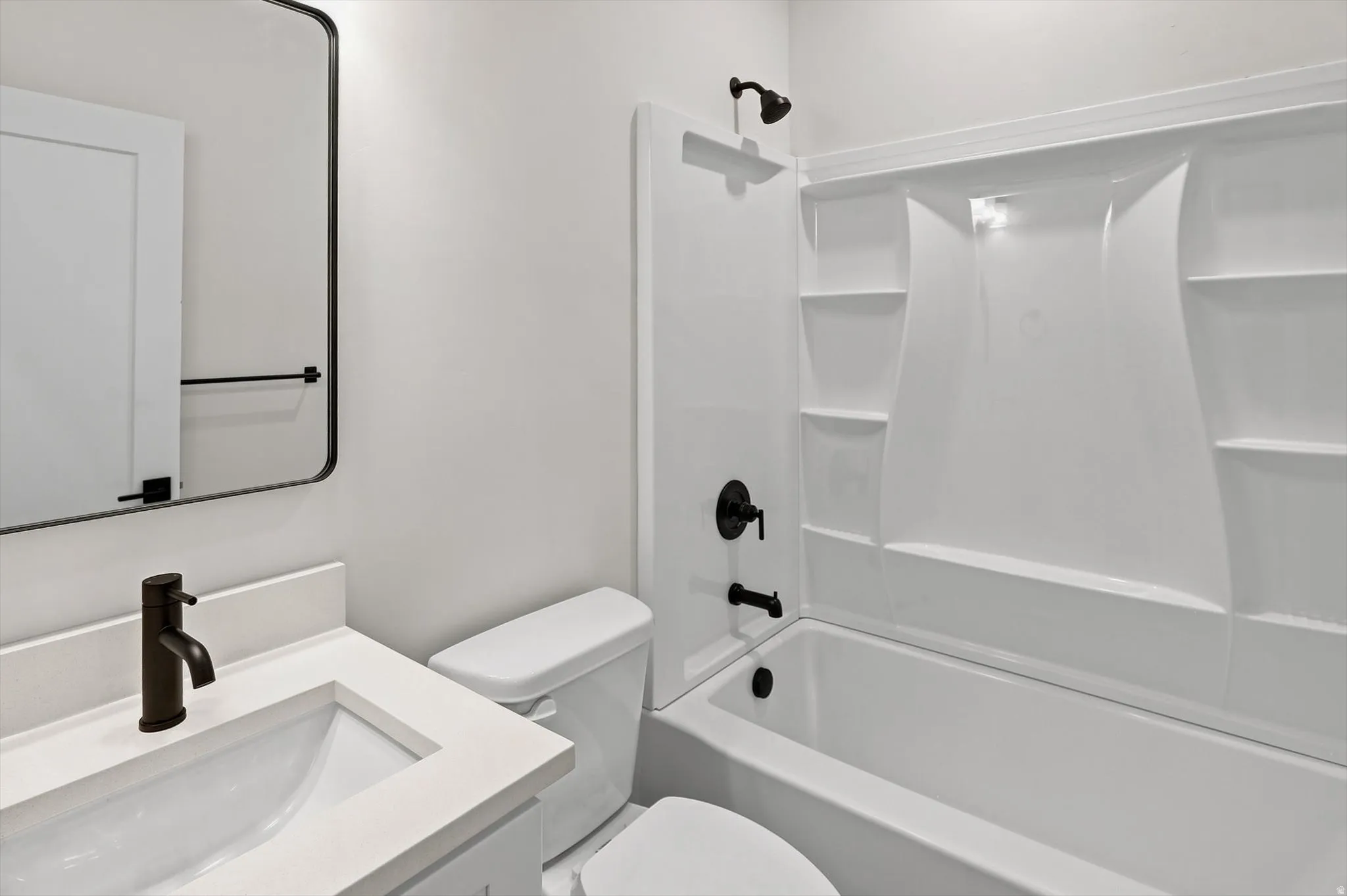 Bathroom with a white vanity featuring a rectangular sink and matte black faucet, framed by a rounded rectangular mirror