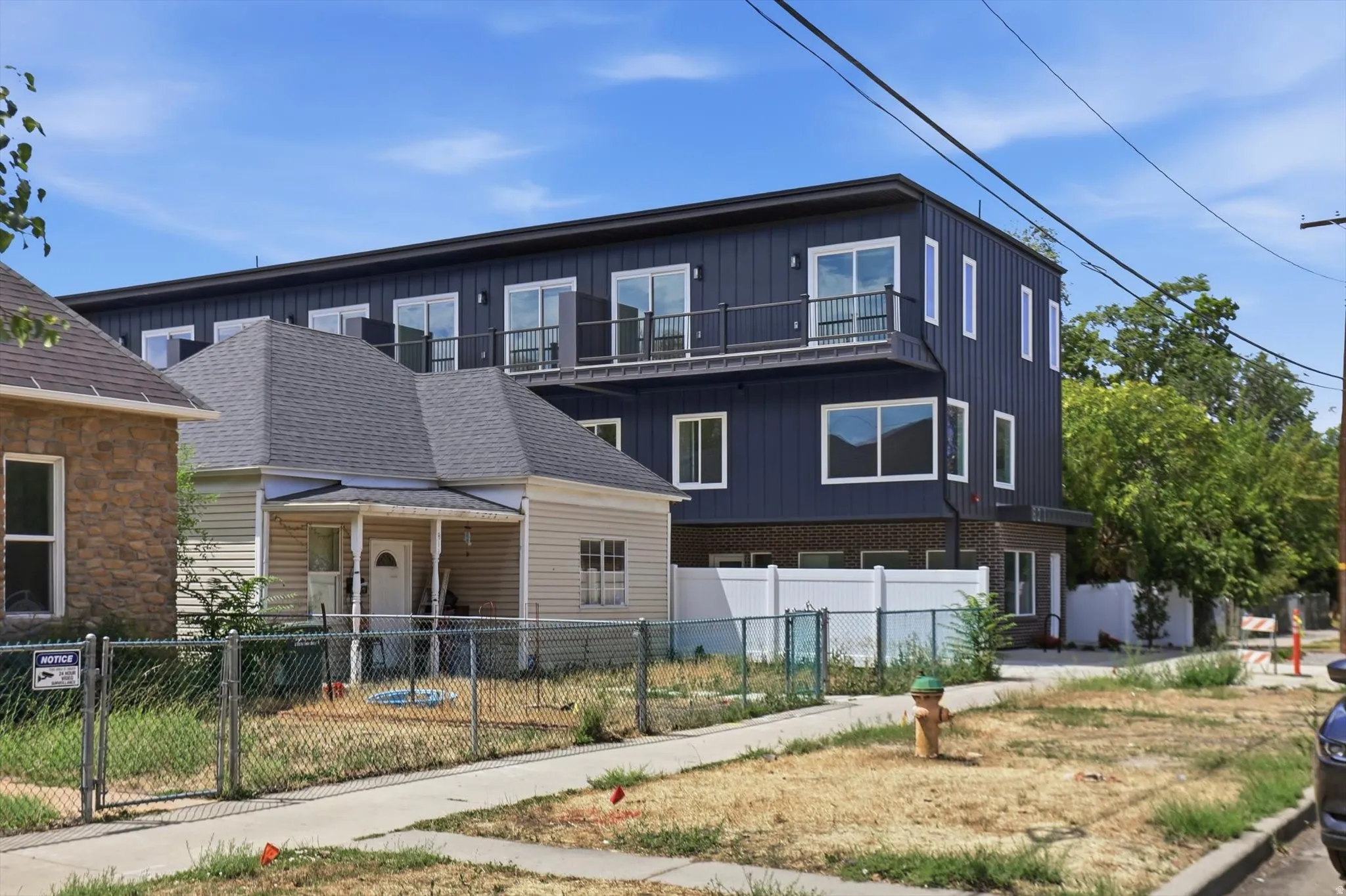 Multi-story property featuring dark vertical siding and a brick base