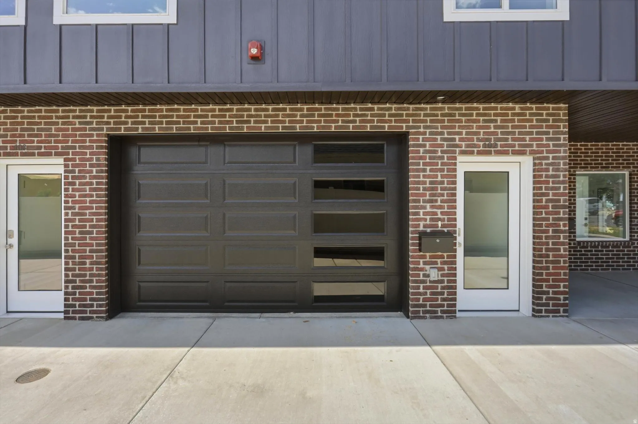 Brick facade with a contemporary black garage door featuring horizontal window panels