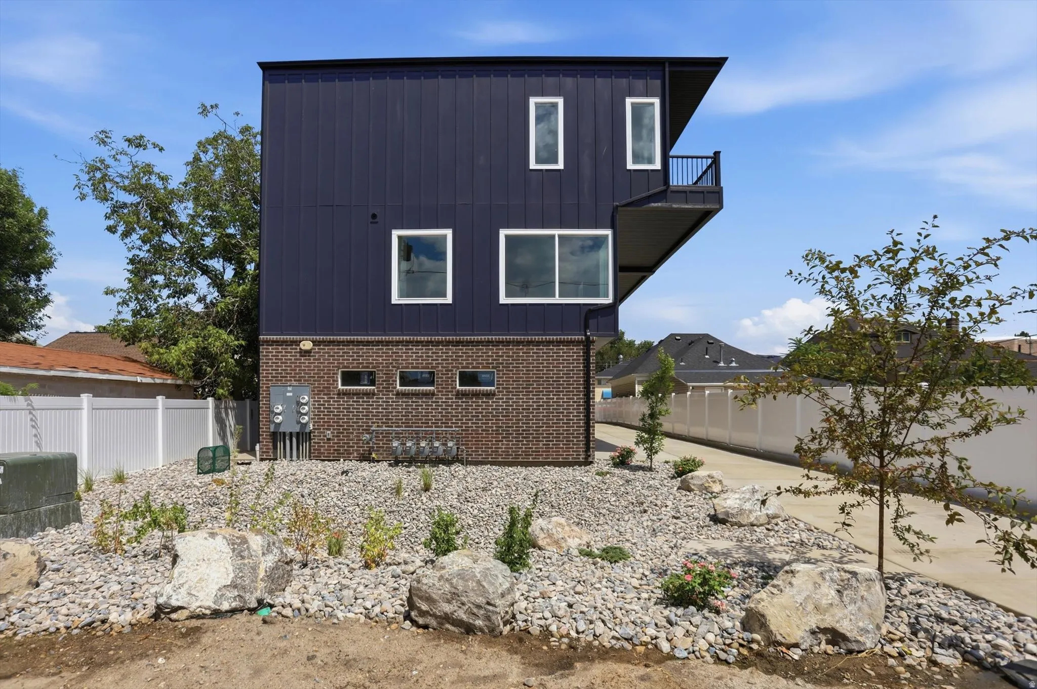 Modern multi-story exterior featuring dark vertical siding and a brick base