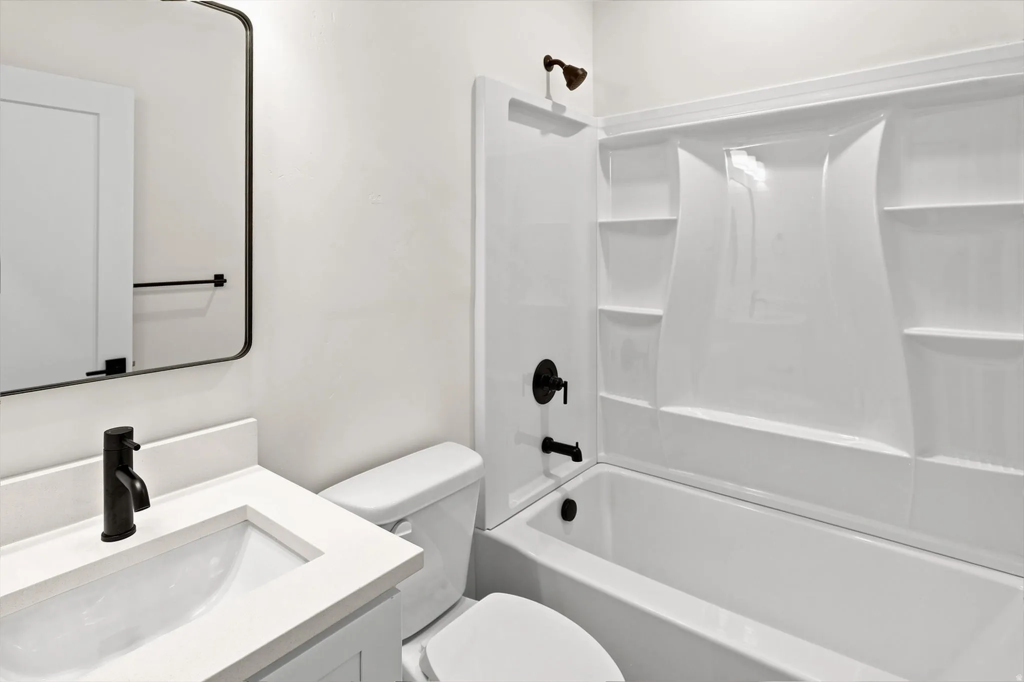 Bathroom featuring a white vanity with an integrated sink, matte black faucet, and a contemporary frameless mirror