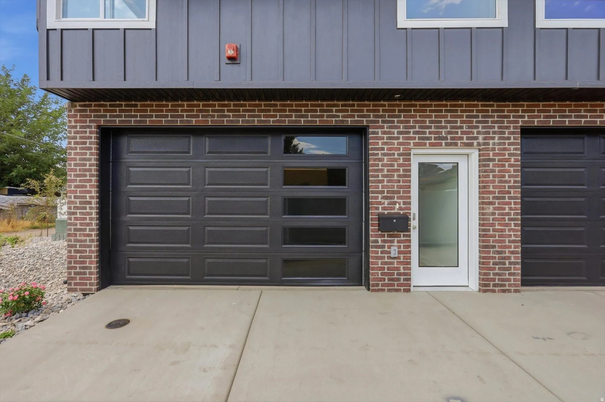 Contemporary exterior featuring a large panel garage door with frosted windows, brick siding, and vertical paneling
