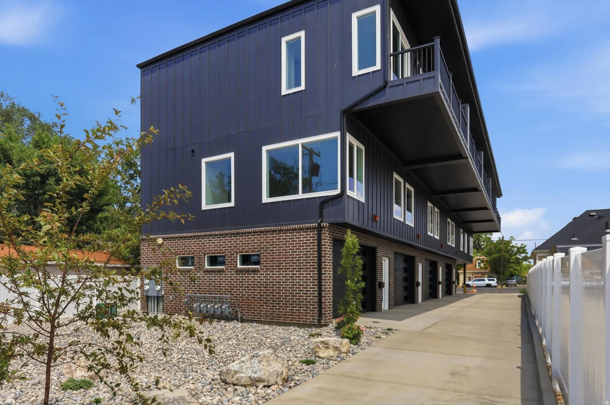 Modern multi-story building featuring dark vertical siding and brickwork